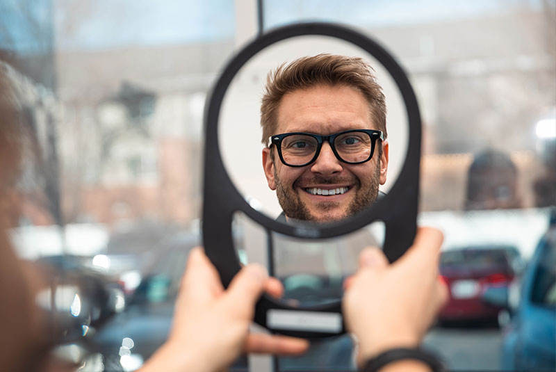 patient smiling in the mirror after their dental procedure