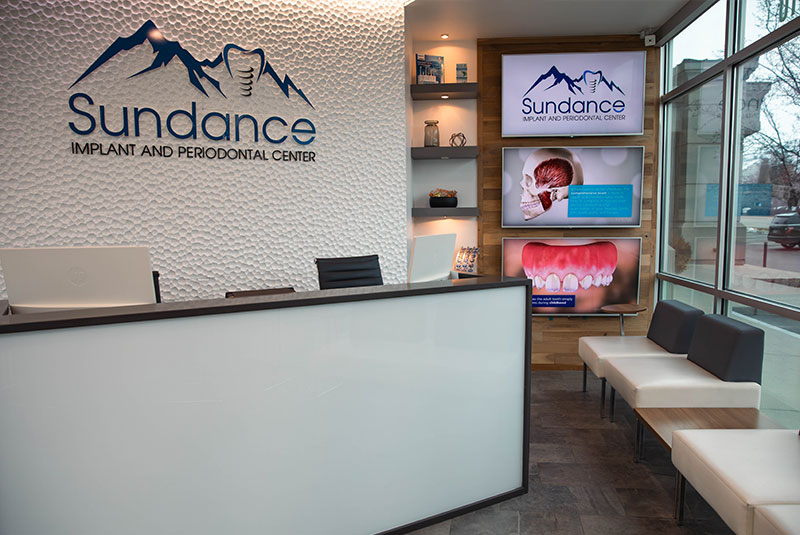Sundance Implant and Periodontal Center dental lobby waiting area and front desk, with logo on wall